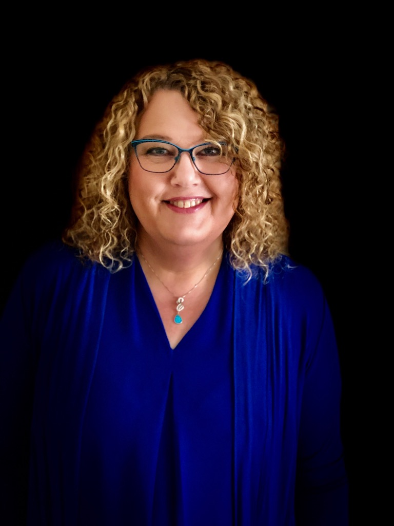 Photo of Beverley Shiels, smiling woman with blonde curly hair and glasses